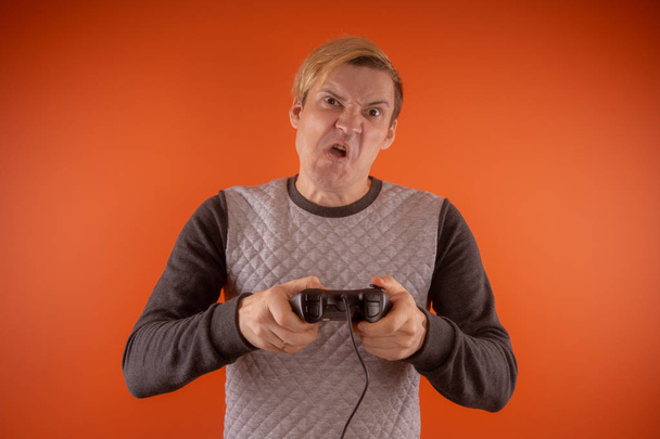 a young guy holding a gamepad in his hands. emotional portrait. man playing computer games. Concept: emotional gamer - Фото, зображення