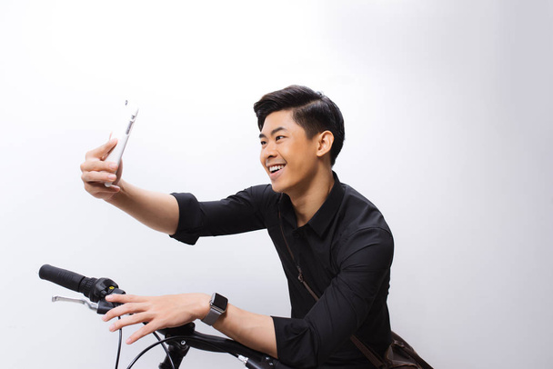 Aasialainen mies seisoo lähellä polkupyörää ja ottaa selfie älypuhelin ac
 - Valokuva, kuva