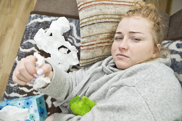 Young woman with headache and flu lying on couch at home. casual style indoor shoot. - Foto, Bild