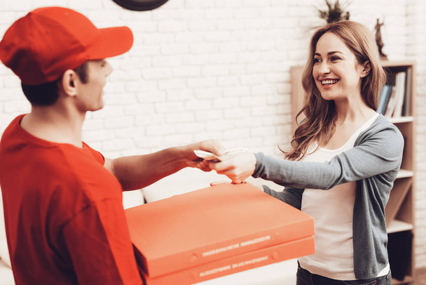 Pizza Delivery. Pizza Deliveryman. Man with Box is Funny Accessory. White Interior. Deliveryman Arab Nationality. Courier in Orange Clothes. Fast Food. Express Delivery. Pizza Delivery Payment. - Photo, Image