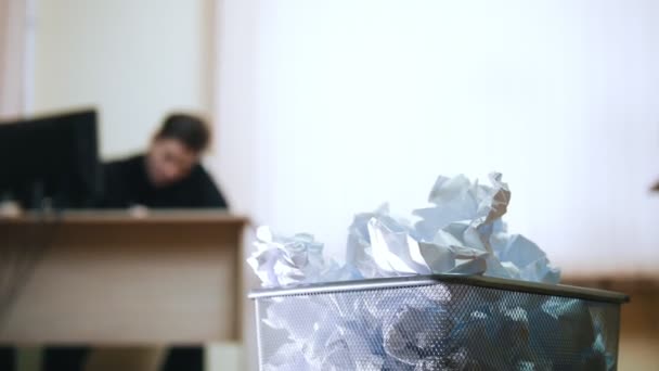 Un homme au bureau écrit quelque chose, froisse le papier et le jette à la poubelle
 - Séquence, vidéo