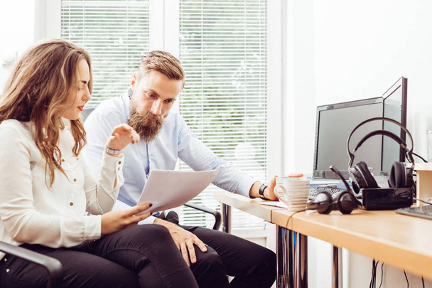 Успешная командная работа: молодой человек и женщина сидят за столом и говорят о работе в офисе
 - Фото, изображение