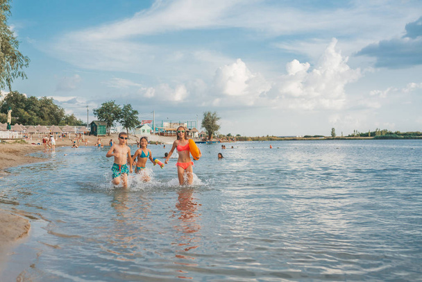 Happy joyful little children playing in the sea, with pleasure splashing the water, enjoying summer holidays on the beach resort, travel and tourism concept - Foto, Bild
