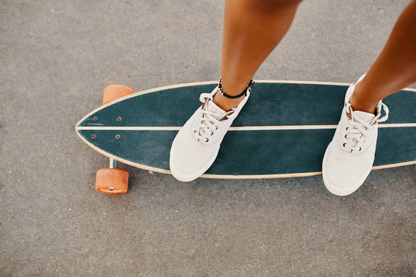Close up de pernas de mulher em tênis brancos no longboard. Copyspace em asfalto
. - Foto, Imagem