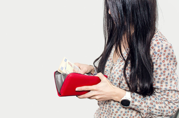 Woman with long black hair puts paper money in a red purse - Photo, Image