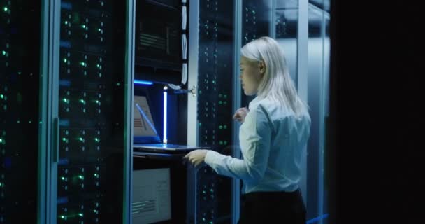 Female technician works on a laptop in a data center - Footage, Video