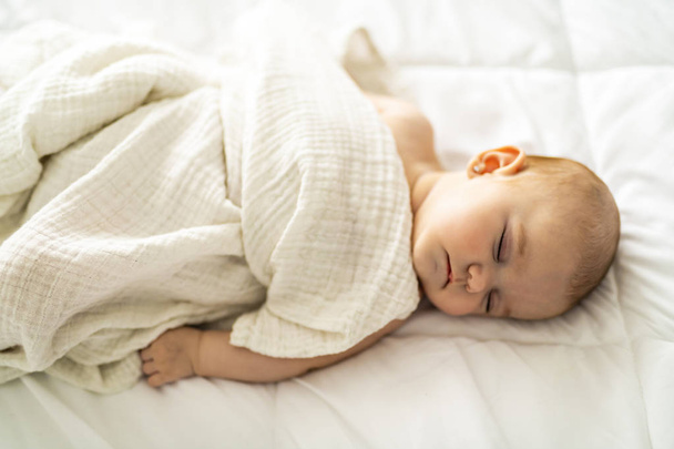 A 4 month baby sleeping on a white bed at home - Foto, imagen