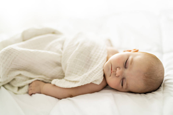Un bebé de 4 meses durmiendo en una cama blanca en casa
 - Foto, Imagen
