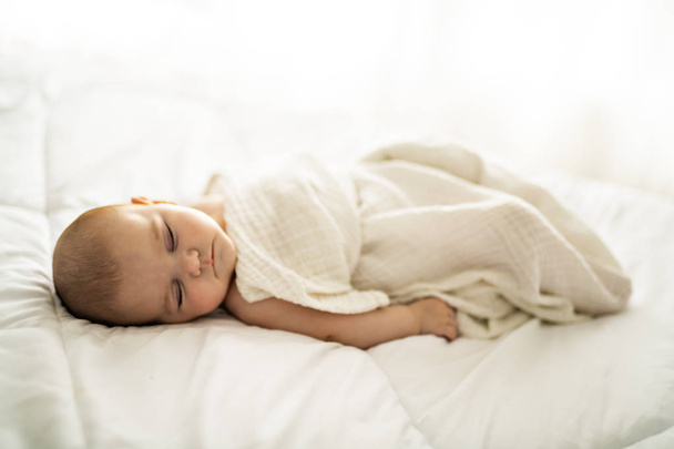 A 4 month baby sleeping on a white bed at home - Valokuva, kuva