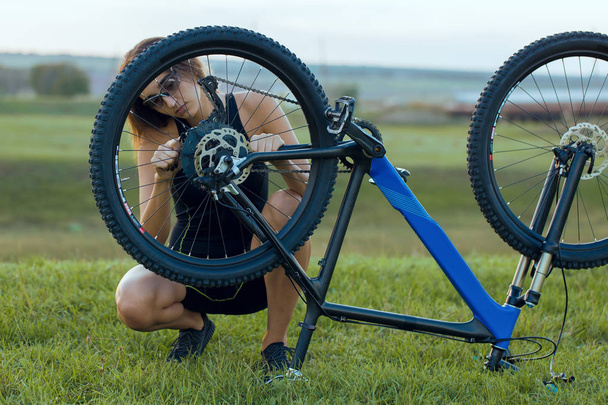 Κορίτσι σε ένα ποδήλατο βουνού σε offroad, όμορφο πορτρέτο ενός ποδηλάτη στο ηλιοβασίλεμα, Fitness κορίτσι βόλτες ποδήλατο βουνού σύγχρονη ινών άνθρακα. - Φωτογραφία, εικόνα