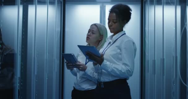 Dvě ženy pracují v datovém centru s řádky serverových rozvaděčích - Záběry, video