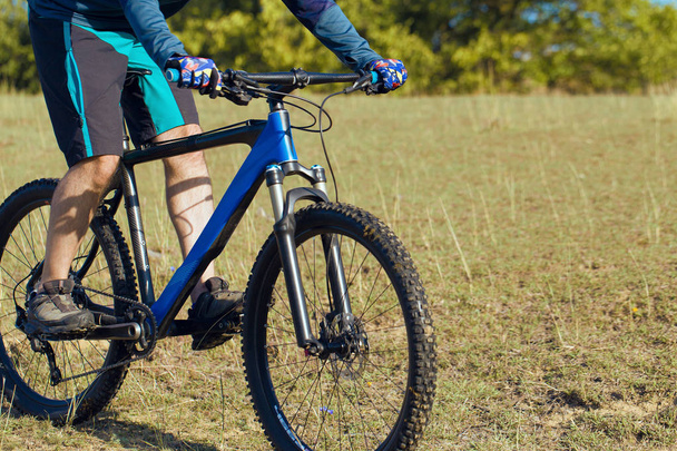 Ciclista en pantalones cortos y jersey en una moderna bicicleta rígida de carbono con horquilla de suspensión neumática
 - Foto, Imagen