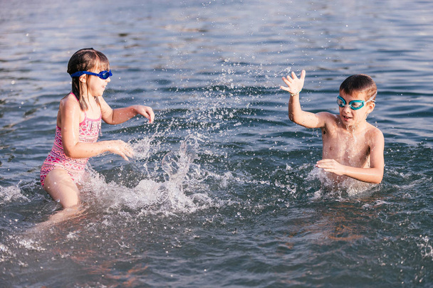 Niños felices jugando en el mar. Niños divirtiéndose al aire libre. Vacaciones de verano y concepto de estilo de vida saludable - Foto, Imagen