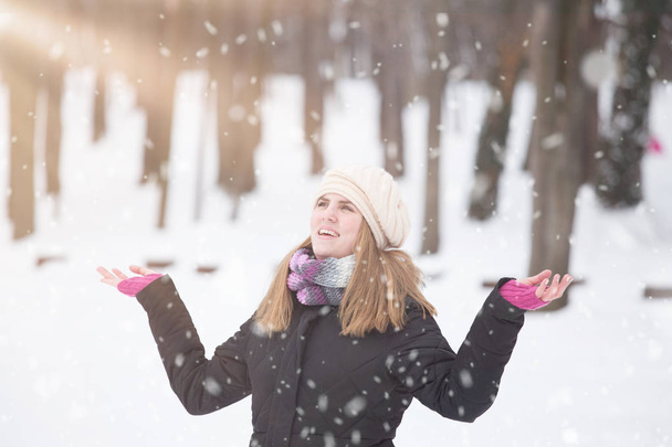 Schnee fällt und niedliche Mädchen fühlen sich glücklich im Freien. - Foto, Bild