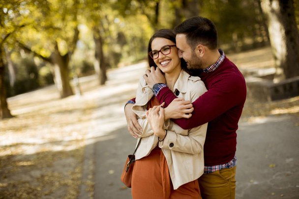 Liebevolle junge Frau und Mann, die Händchen haltend durch den Stadtpark gehen - Foto, Bild