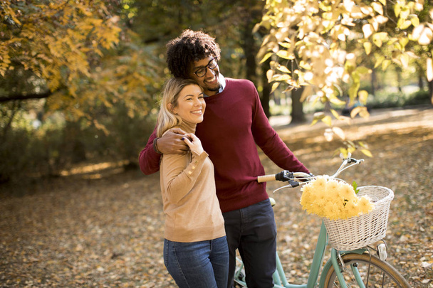 Jeune couple multiracial marchant à travers le parc et poussant un vélo
 - Photo, image