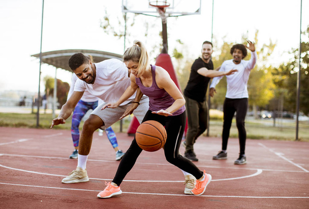 Groep multiraciale jongeren spelen basketbal op het Hof in de open lucht - Foto, afbeelding