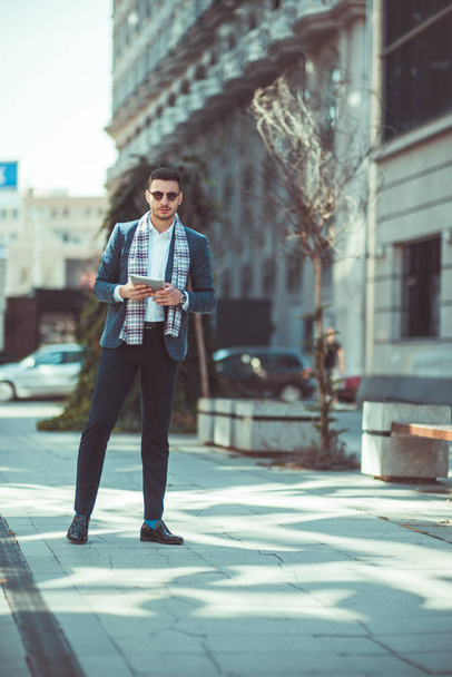 ein Mann hält sein Notizbuch in der Hand und geht auf dem Stadtplatz spazieren, genießt die Aussicht und blickt vor sich hin - Foto, Bild