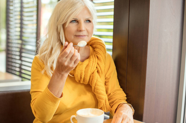 Stylish gorgeous senior woman posing indoors with mug of coffee. Elderly people, modern lifestyle, beauty and fashion concept. - 写真・画像