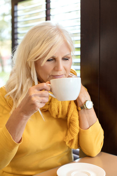 Стильна розкішна старша жінка позує в приміщенні з чашкою кави. Літні люди, сучасний спосіб життя, краса та концепція моди
. - Фото, зображення