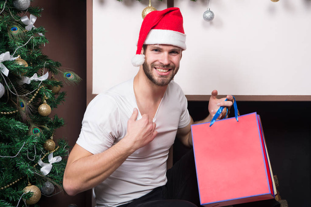 online christmas shopping. New year scene with tree and gifts. happy santa man. man in santa hat hold christmas present. The morning before Xmas. delivery christmas gifts. Are you ready - Foto, Imagen
