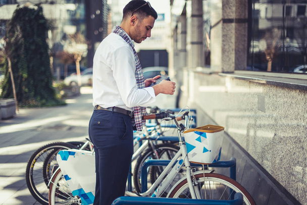 Um empresário urbano está lendo um folheto enquanto está ao lado de algumas bicicletas estacionadas
 - Foto, Imagem