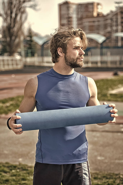 man with muscular body, beard holding yoga or fitness mat - Fotó, kép