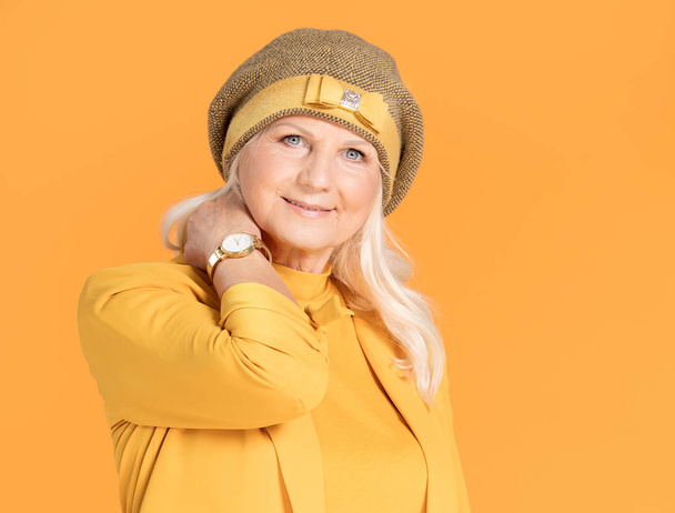 Smiling mature woman in yellow beret posing in studio. - Zdjęcie, obraz