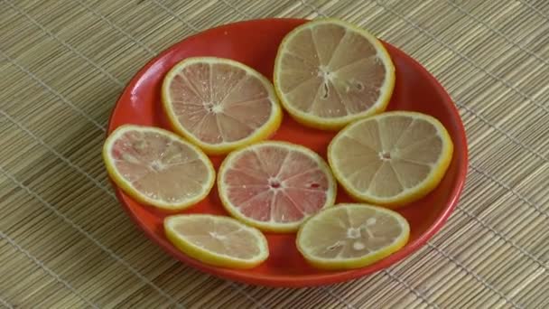 Rodajas de limón frescas girando en plato rojo sobre fondo de bambú
 - Metraje, vídeo