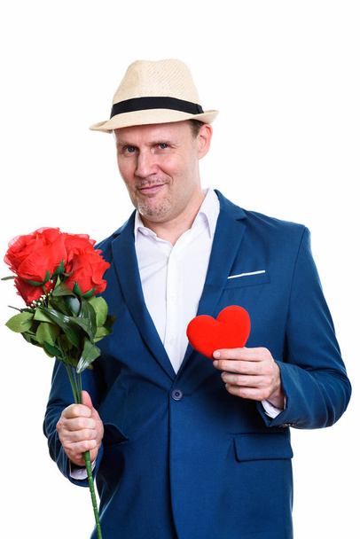 Студійний знімок зрілого бізнесмена, що тримає червоні троянди і серце
 - Фото, зображення