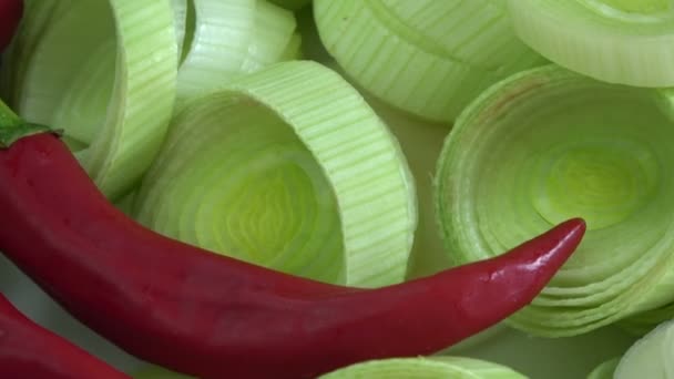 Świeży plasterek pora i czerwona papryka chili obracające się tło - Materiał filmowy, wideo