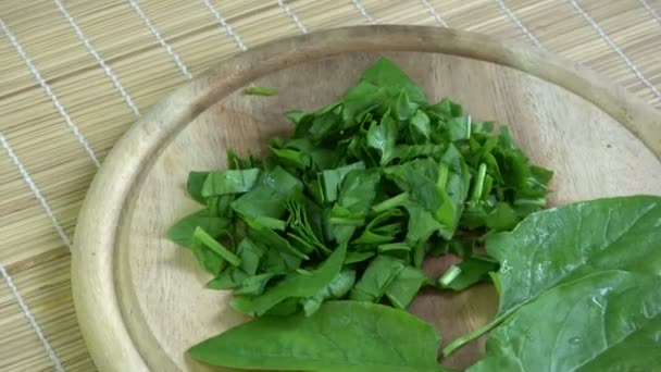 Rotating fresh healthy chopped cutted spinach leaves on wooden chopping board - Footage, Video