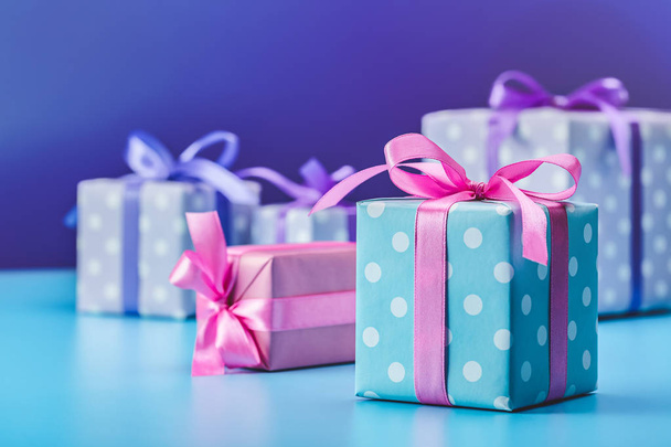 Festive background, gifts in boxes, packed in pink and blue in polka dot, decorated with ribbons and bows. - Fotografie, Obrázek