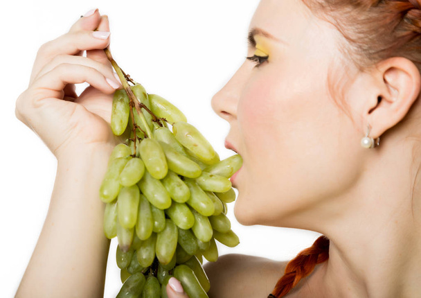 Beautiful redhead woman licks grapes. concept of healthy eating - Foto, Imagem
