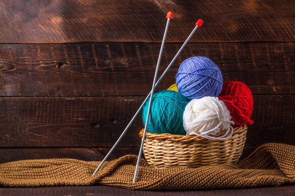 Fil de couleur pour tricoter, écharpe tricotée, aiguilles à tricoter sur un fond sombre. Espace de copie. Concept de tricot
 - Photo, image