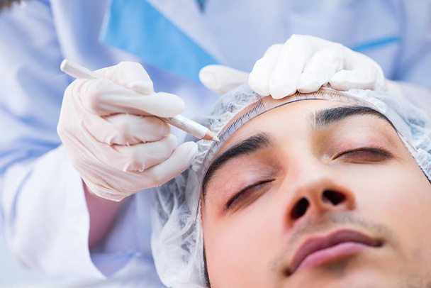 Médico que mede o rosto dos pacientes antes da cirurgia plástica
 - Foto, Imagem