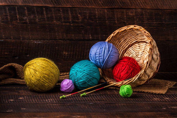 Bright, colored thread for knitting and knitting needles for knitting on a dark, wooden background. Knitting concept - Photo, image
