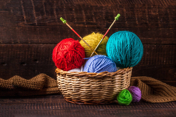 Bright, colored thread for knitting in a basket and knitting needles on a dark background. Knitting - Photo, image