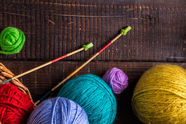 Colored thread for knitting and knitting needles for knitting on a dark, wooden background. Knitting concept. Top view - Photo, image