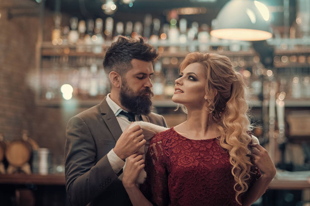 Young hipster couple in a cafe. He puts a fur on her shoulders, she is looking. Love or friendship concepts. - Photo, image