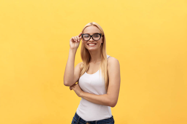 Gelukkig stijlvolle moderne vrouw met moderne gevormde zonnebril lachen kijken naar je camera geïsoleerd op gele achtergrond. Geluk concept - Foto, afbeelding