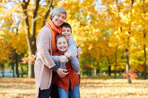 Mutlu aile sonbahar Şehir Parkı içinde yürür. Çocuklar ve ebeveynler poz, gülümseyen, oyun ve eğlenmek. Parlak sarı ağaçlar. - Fotoğraf, Görsel