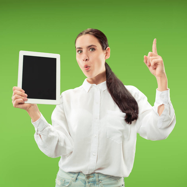 Portrait of a confident casual girl showing blank screen of laptop isolated over green background - Foto, immagini