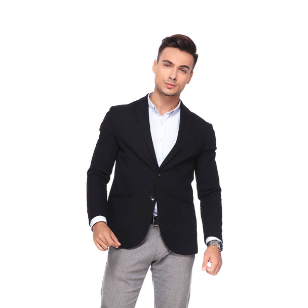 Porträt eines jungen Geschäftsmannes im schwarzen Anzug, der sich auf weißem Hintergrund zur Seite lehnt - Foto, Bild