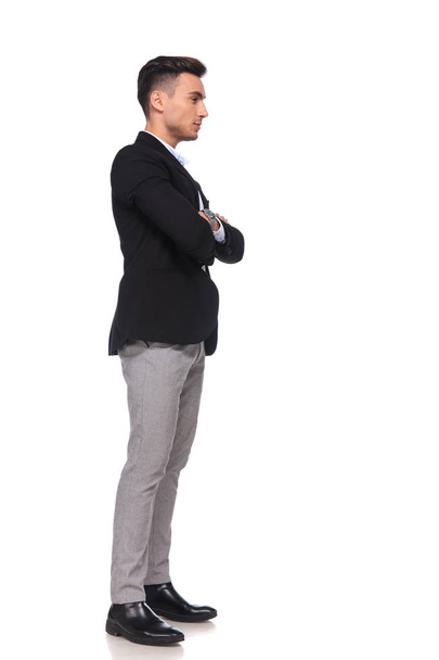 homem de negócios confiante com as mãos dobradas esperando na fila enquanto estava em pé sobre fundo branco, imagem de comprimento total
 - Foto, Imagem