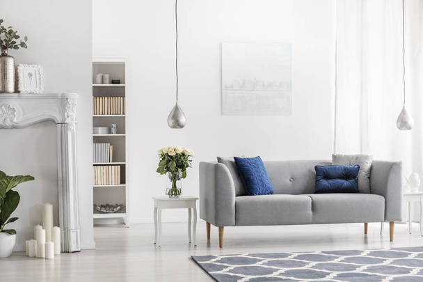 Canapé gris avec coussins bleus dans le salon élégant blanc intérieur avec des fleurs et de la peinture. Une vraie photo
 - Photo, image