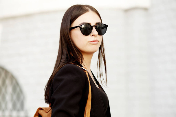 Beautiful young student hipster girl with healthy straight hair wearing a black jacket and sunglasses. Street style - Photo, Image