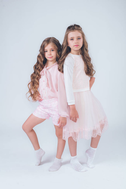 Cute little girls with curly hair in fashionable clothes of white and pink in the studio - Foto, Bild