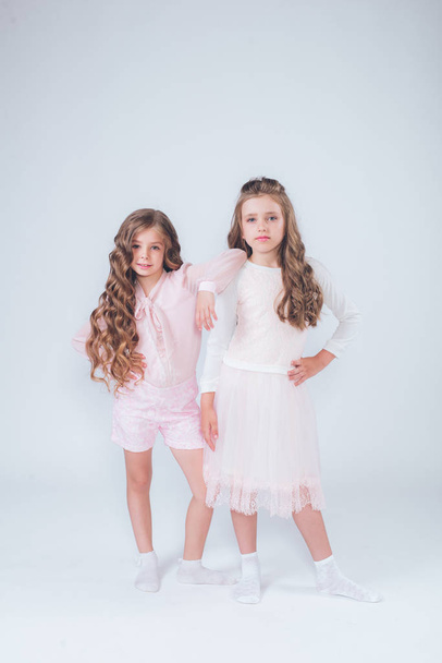 Cute little girls with curly hair in fashionable clothes of white and pink in the studio - Foto, immagini