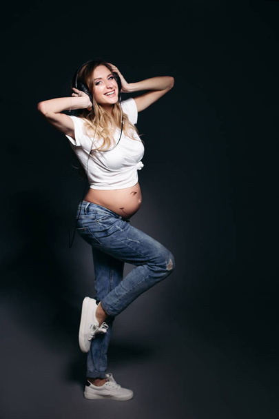 Pregnant woman posing with naked tummy and smiling. - Valokuva, kuva